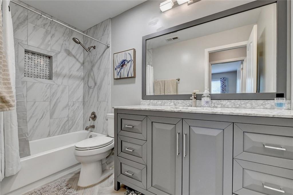 Renovated bathroom with marble-look tile and a new vanity